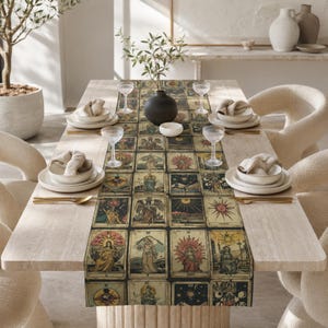 May include: A rectangular table runner featuring a repeating grid of vintage-style tarot card illustrations in muted tones of gold, brown, and black. The runner is centered on a light-colored stone dining table with place settings and glassware.