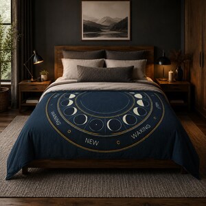 May include: A dark blue bedspread featuring a large circular graphic of the lunar cycle. The design includes white moon phases arranged in a ring with the text "WANING," "NEW," and "WAXING" printed in white capital letters along the outer edge.