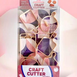 Könnte beinhalten: Eine transparente Kunststoffverpackung mit mehreren goldfarbenen Bastel-Ausstechern in Form von Miniatur-Schneidebrettern. Die Verpackung trägt den Text "Craft Cutter by Smarta" und "Chopping Board Cutters".