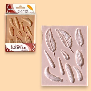 Pode incluir: Forma de silicone para fazer formas de penas. A forma é rosa e tem 10 formas de penas diferentes. A forma é etiquetada "Silikon Kalıplar by Smarta".