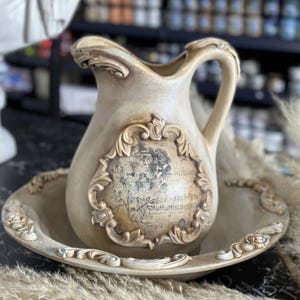Peut inclure: Un pichet en c&eacute;ramique blanche avec un motif floral et un bol en c&eacute;ramique blanche assorti. Le pichet a une anse et un bec verseur. Le bol a un bord festonn&eacute;.