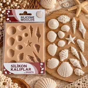Könnte beinhalten: Eine rechteckige, beige Silikonform zum Basteln mit verschiedenen Muschel- und Seesternformen. Die Verpackung zeigt den Text SEASHELLS SILICONE MOULDS und SILIKON KALIPLAR by SMARTA. Neben der Form liegen mehrere weiße, geformte Muschelfiguren.