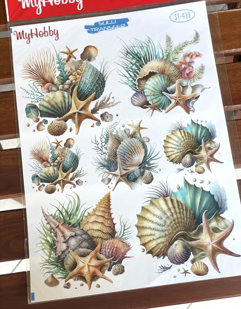 May include: A sheet of six colourful seashell and starfish transfer decals. The decals feature a variety of seashells, starfish, and seaweed in shades of blue, green, brown, and white.