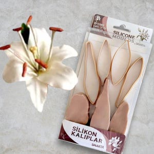 Może przedstawiać: Biały kwiat lilii obok opakowania silikonowych foremek i wykrawaczy do liści. Opakowanie zawiera tekst "SILICONE MOULDS" i "LILY FLOWER LEAVES CUTTER". Foremki i wykrawacze mają różne kształty do tworzenia płatków i liści.