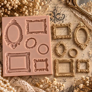 May include: A light pink silicone mould featuring various recessed shapes for casting miniature ornate frames, including rectangular, oval, and circular designs, alongside several finished gold-coloured miniature frames cast from the mould.