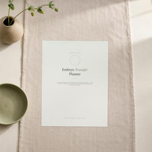 May include: A white rectangular planner page titled Embryo Transfer Planner in dark grey text. The page features a circular icon, a subtitle, and a paragraph of text below the title. The document is printed on a light-coloured paper sheet.