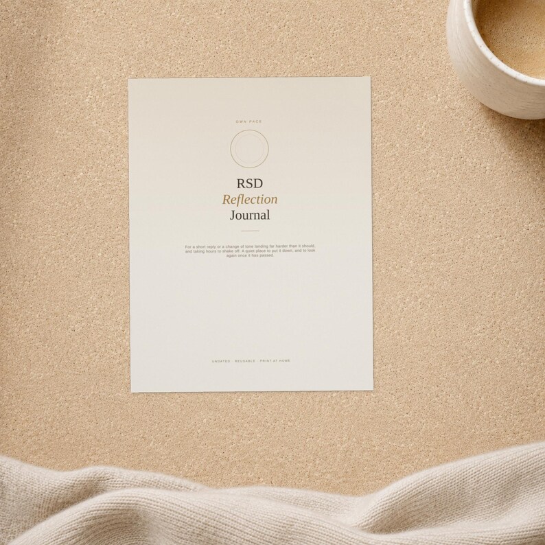 May include: A rectangular paper journal cover in a light cream colour featuring a thin circular outline, the text RSD Reflection Journal, and smaller printed text below. The design is centred on the page with a clean, minimalist layout.
