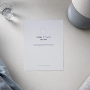 Op de afbeelding: Een wit rechthoekig vel papier met de titel Energy & Pacing Tracker in donkergrijze tekst. Het ontwerp bevat een dunne cirkelvormige omtrek, een kleine horizontale lijn en een alinea met kleine tekst onder de titel, met de woorden digital, printable, print at home onderaan.