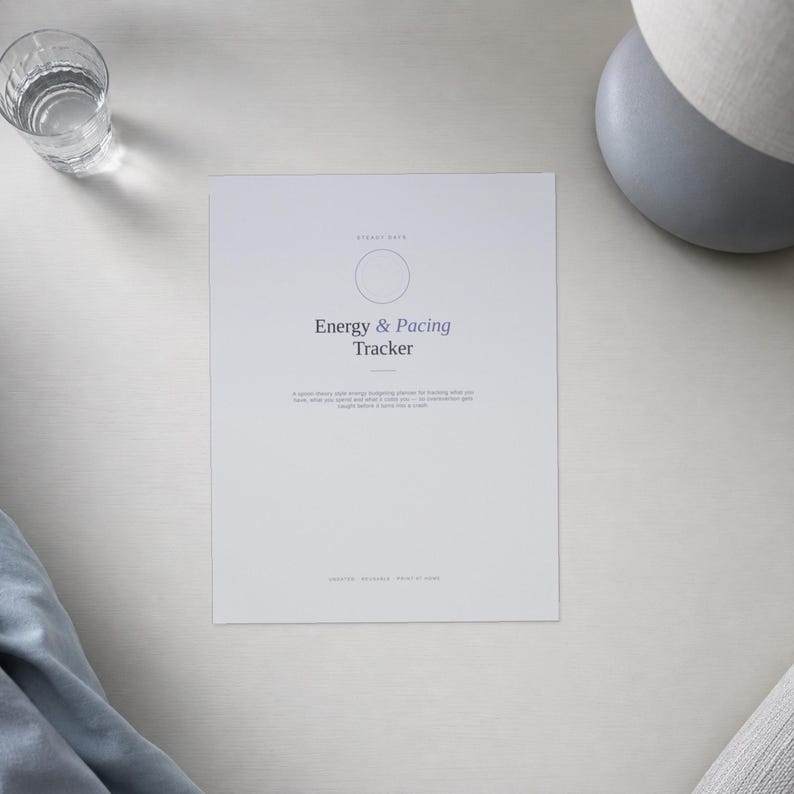 Op de afbeelding: Een wit rechthoekig vel papier met de titel Energy & Pacing Tracker in donkergrijze tekst. Het ontwerp bevat een dunne cirkelvormige omtrek, een kleine horizontale lijn en een alinea met kleine tekst onder de titel, met de woorden digital, printable, print at home onderaan.