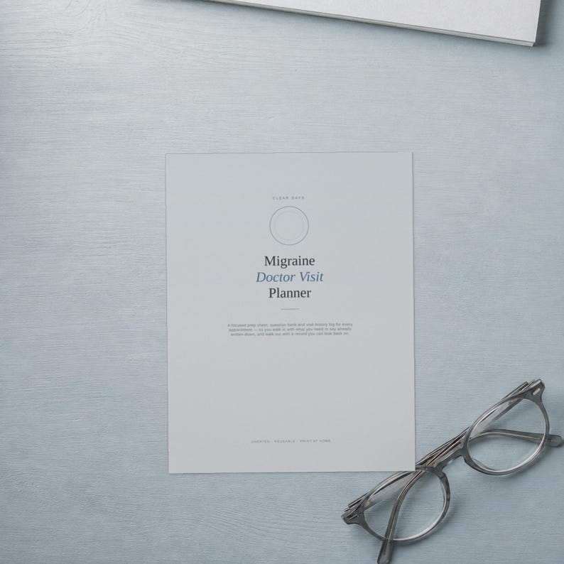 May include: A light grey Migraine Doctor Visit Planner document featuring a circular icon, centred text, and a small horizontal line. Beside the document sits a pair of clear-framed glasses with thin metal temples, positioned on a light grey surface.