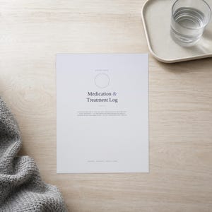 May include: A white paper sheet titled Medication & Treatment Log with a circular outline at the top, descriptive text below the title, and small footer text at the bottom, presented in a clean, minimalist layout with dark grey typography.