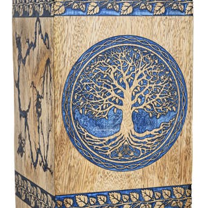 Può includere: Una scatola di legno con un design ad albero della vita blu e marrone. La scatola ha un bordo blu con un motivo a foglie.