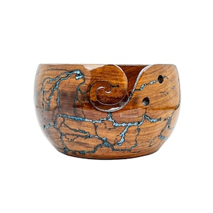 May include: A wooden yarn bowl with a blue and brown swirl pattern. The bowl has a carved spiral for holding yarn.