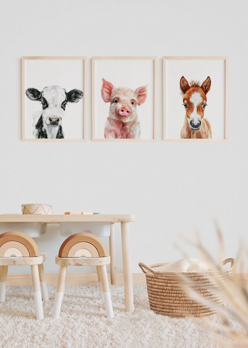 以下が含まれることがあります： 農場の動物を描いた水彩画が3枚、額装されています。絵は、牛、豚、子馬です。絵は、白い壁に、木製のテーブルと2脚の木製の椅子の上に飾られています。