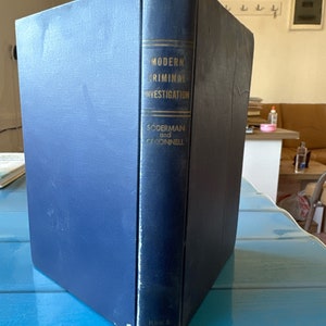 Op de afbeelding: Een blauw hardback boek getiteld "Modern Criminal Investigation" door "Söderman en O'Connell", uitgegeven door "Funk & Wagnalls".