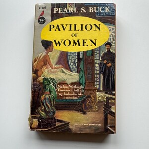 Puede incluir: Una portada de libro de bolsillo vintage con fondo amarillo y el título "Pabellón de Mujeres" de Pearl S. Buck. La portada presenta una ilustración de una mujer con un vestido tradicional chino y un hombre con una túnica larga.