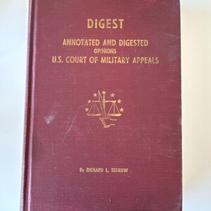 Op de afbeelding: Een bordeauxrood boek getiteld "Digest Annotated and Digested Opinions U.S. Court of Military Appeals" door Richard L. Tedrow. De omslag toont een gouden illustratie van een weegschaal met een zwaard en sterren.