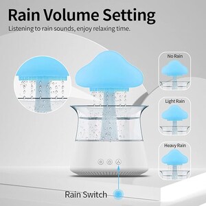 May include: A white humidifier shaped like a vase with a blue silicone cloud on top. The cloud has a small hole in the center where water droplets fall into the vase. The humidifier has three buttons on the front: a sun, a power button, and a moon. The text "Rain Switch" is below the humidifier. There are three images of the cloud with different levels of water droplets: "No Rain", "Light Rain", and "Heavy Rain".