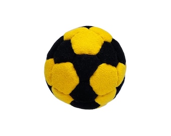 Könnte beinhalten: Ein Plüschball mit einem klassischen geometrischen Muster aus abwechselnd schwarzen und gelben fünfeckigen und sechseckigen Feldern. Die Oberfläche hat eine weiche, flauschige Textur und die Kugel ist mit sichtbaren Nähten zwischen den Stoffteilen gefertigt.