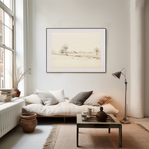 May include: A black framed print of a minimalist landscape drawing hangs above a white linen futon with a wooden frame. The futon is styled with white and gray throw pillows. A wooden coffee table with a rustic finish sits in front of the futon. A floor lamp with a black shade stands next to the futon.