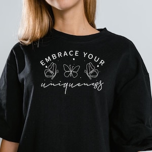 May include: Black oversized t-shirt with white text that reads "Embrace Your Uniqueness" and three butterfly illustrations.