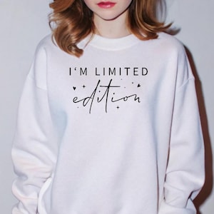 May include: White sweatshirt with the text "I'm limited edition" in black script with small hearts and stars.