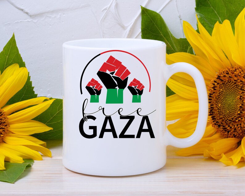 May include: White ceramic mug with a black, red, and green fist graphic and the text "free GAZA" in black.