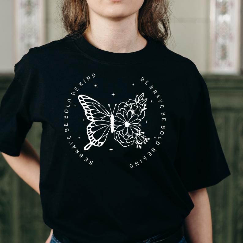 May include: Black t-shirt with a white graphic design of a butterfly and flowers. The text around the design reads "Be Brave Be Bold Be Kind".