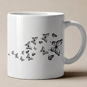 Puede incluir: Taza de cer&aacute;mica blanca con un dise&ntilde;o de mariposa negra. Las mariposas est&aacute;n dispuestas en un patr&oacute;n fluido, creando una sensaci&oacute;n de movimiento.