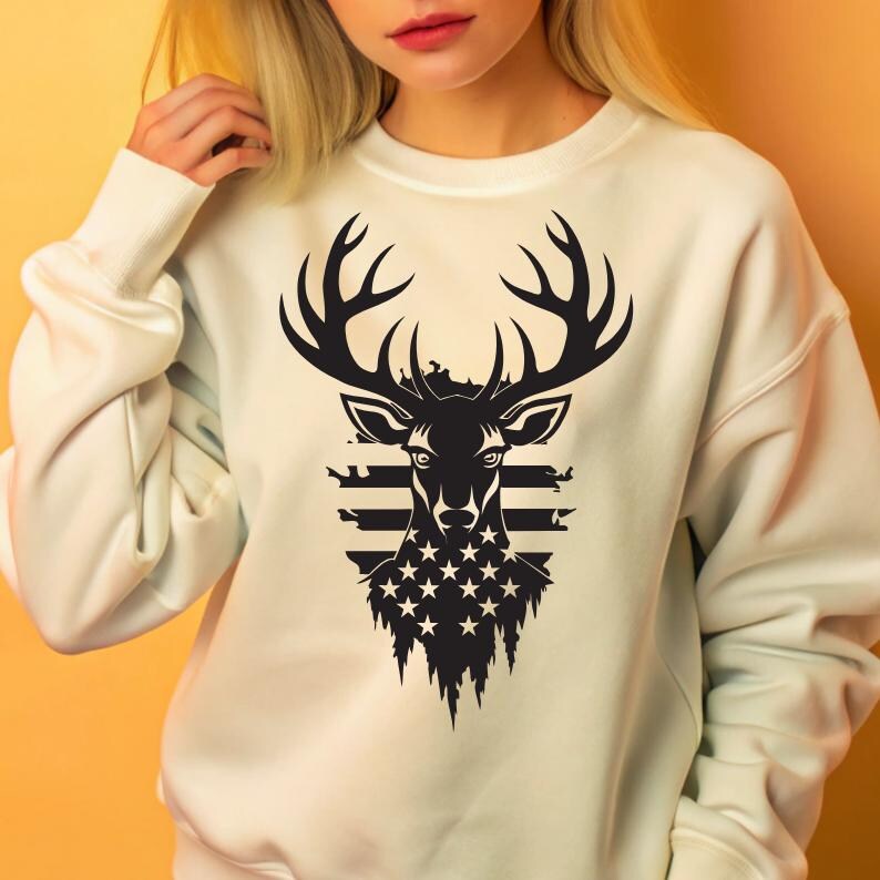 May include: White sweatshirt with a black and white graphic of a deer head with antlers. The deer head is superimposed over an American flag design.