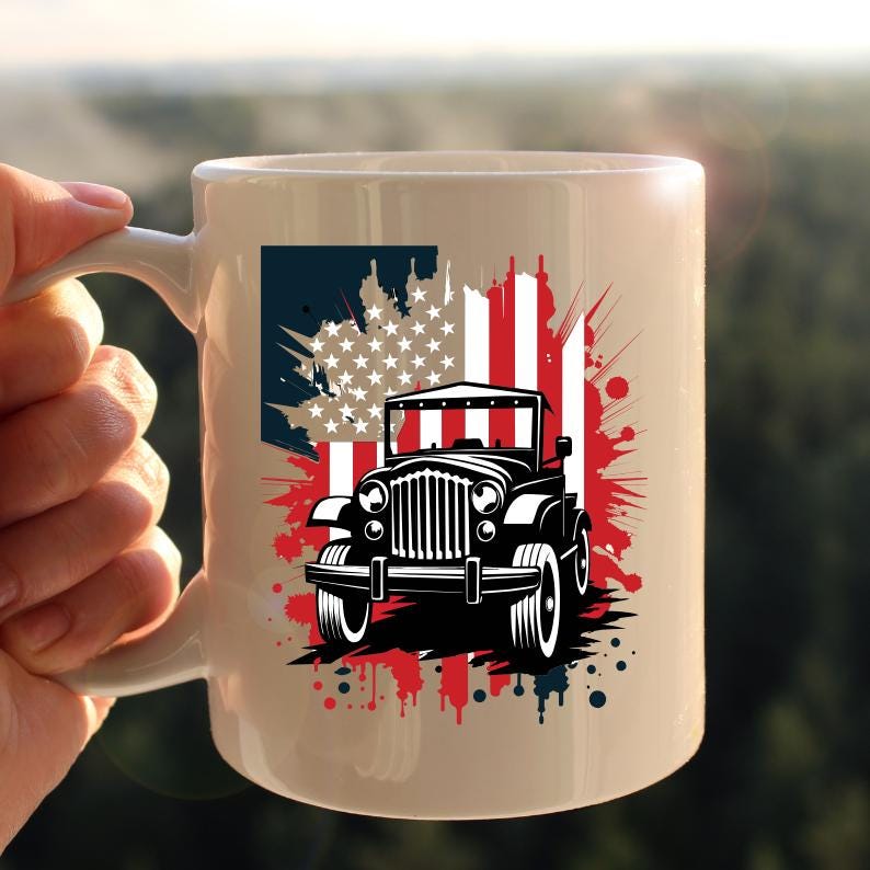 May include: A white ceramic mug with a black and white illustration of a jeep driving through a red, white, and blue American flag. The flag is stylized with paint splatters.