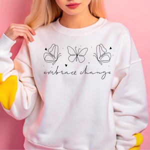 May include: White sweatshirt with a black line drawing of three butterflies and the text "embrace change".