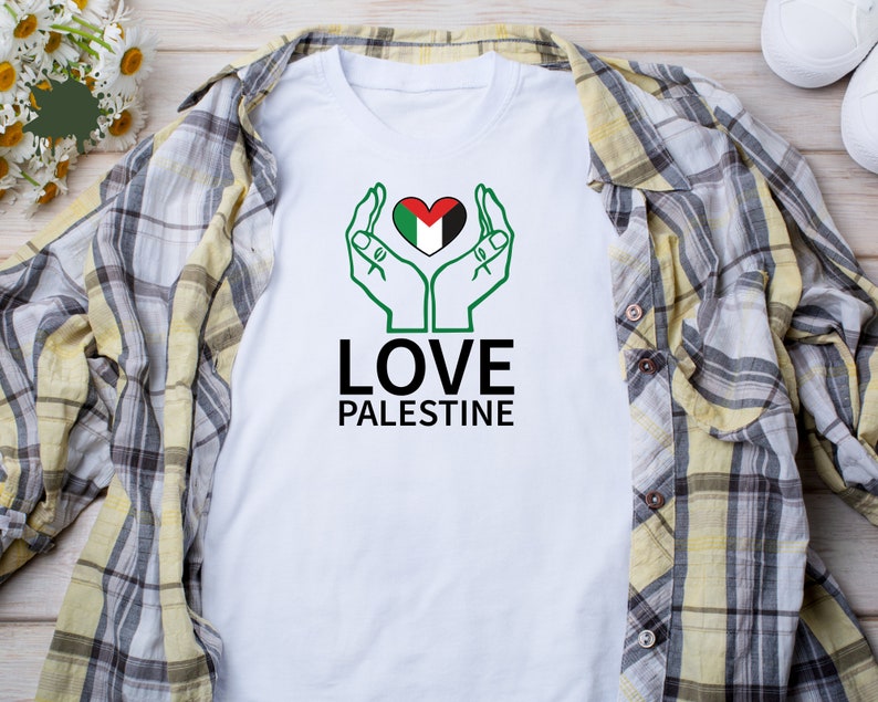 May include: White t-shirt with a green, black, and white heart with hands around it. The text "LOVE PALESTINE" is below the heart.