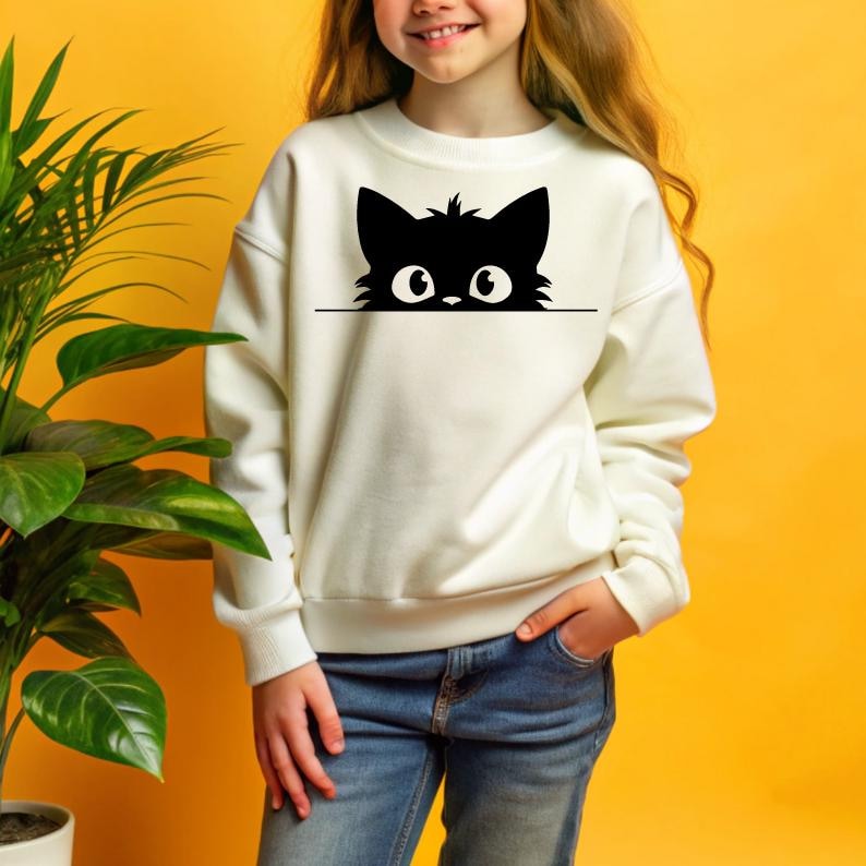K&ouml;nnte beinhalten: Wei&szlig;er Pullover mit einer schwarzen Comic-Katze, die &uuml;ber den oberen Rand schaut. Die Katze hat gro&szlig;e Augen und eine kleine Nase.