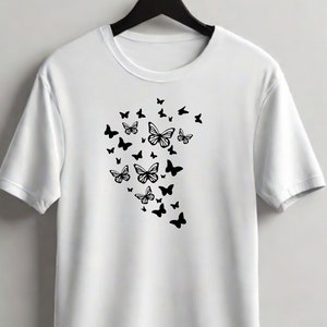Puede incluir: Camiseta blanca con un dise&ntilde;o de mariposa negra. Las mariposas est&aacute;n agrupadas en forma de coraz&oacute;n.