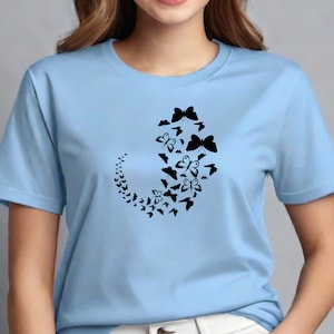 Puede incluir: Una camiseta azul claro con un dise&ntilde;o negro de un patr&oacute;n de mariposas en espiral.