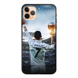 Op de afbeelding: Een zwarte telefoonhoes met een foto van een voetballer die een trofee vasthoudt. De speler draagt een wit shirt met nummer 7 en de naam "RONALDO" op de rug. De achtergrond is een wazige afbeelding van een stadion.
