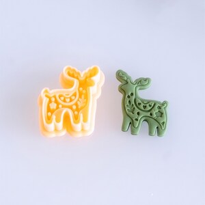 Scandi folk deer polymer clay cutter with matching finished clay piece in moss green color on a clean background