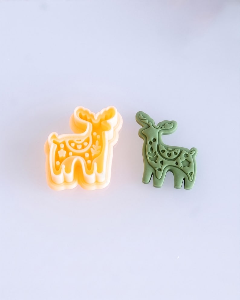 Scandi folk deer polymer clay cutter with matching finished clay piece in moss green color on a clean background