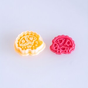 Scandi folk hedgehog polymer clay cutter with finished clay piece in vibrant pink, featuring bold and playful imprint design