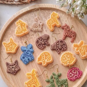 Polymer clay earrings made with scandi folk animal cutters, showing a full set of nordic style deer, fox, hedgehog and bear designs