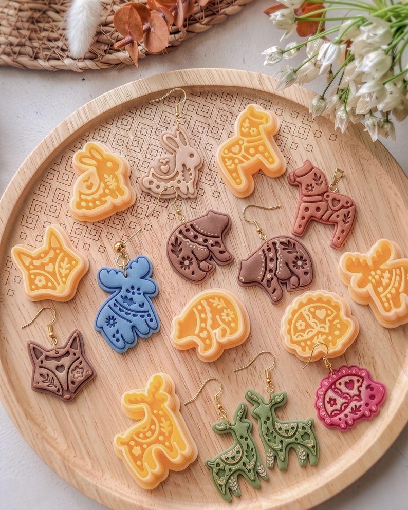 Polymer clay earrings made with scandi folk animal cutters, showing a full set of nordic style deer, fox, hedgehog and bear designs