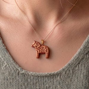 Scandi folk horse pendant necklace worn on neck, showing polymer clay jewelry made with animal cutter design
