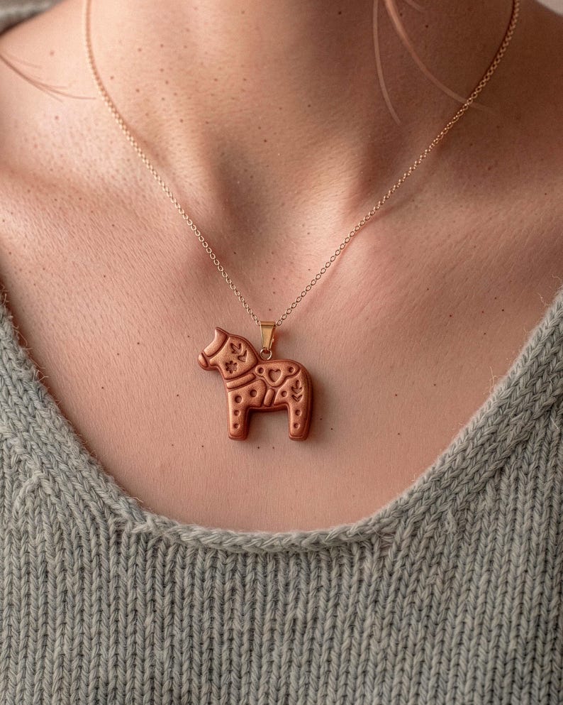 Scandi folk horse pendant necklace worn on neck, showing polymer clay jewelry made with animal cutter design