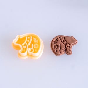 Scandi folk bear polymer clay cutter with finished clay piece in warm mocha brown, showing soft matte texture and detailed imprint