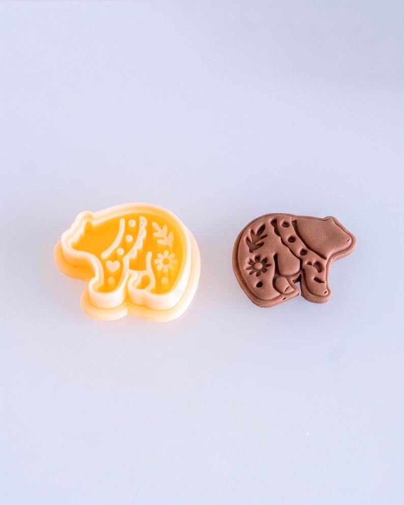 Scandi folk bear polymer clay cutter with finished clay piece in warm mocha brown, showing soft matte texture and detailed imprint