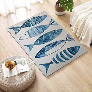 Puede incluir: Una alfombra azul y blanca con un dise&ntilde;o de acuarela de cinco peces. Los peces est&aacute;n dispuestos en forma escalonada y tienen diferentes dise&ntilde;os.