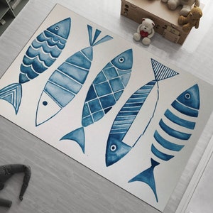 Puede incluir: Una alfombra blanca con cinco dise&ntilde;os de peces azules en acuarela. Los peces son estilizados y tienen diferentes patrones.