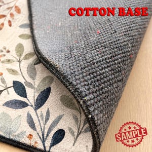 a close-up view of a gray, textured fabric with a floral pattern, likely a cotton base rug.
