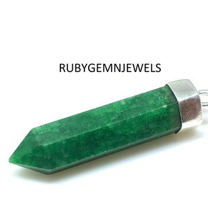 Op de afbeelding: Een groene edelsteen hanger met een zilverkleurige dop en lus. De edelsteen heeft een levendige smaragdgroene kleur en is in een zeshoekige vorm gesneden. De tekst "RUBYGEMNJEWELS" staat op de afbeelding.